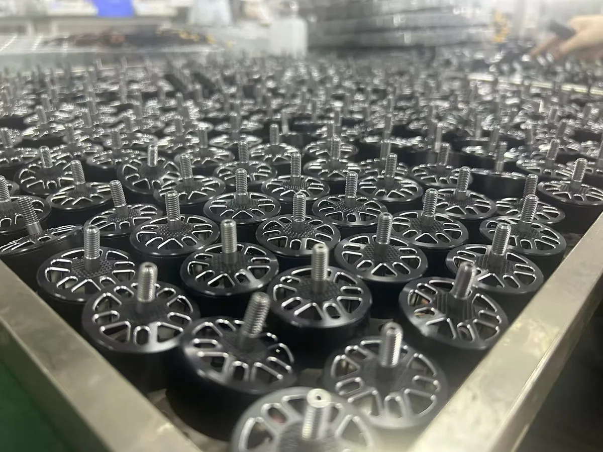 Close-up of outrunner motor rotor bells with aluminum end caps and threaded shafts, mass produced in the Yadovex factory