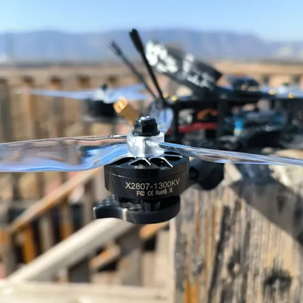 X2807 1300KV FPV brushless motor mounted on a drone with a transparent propeller, outdoor flight scene